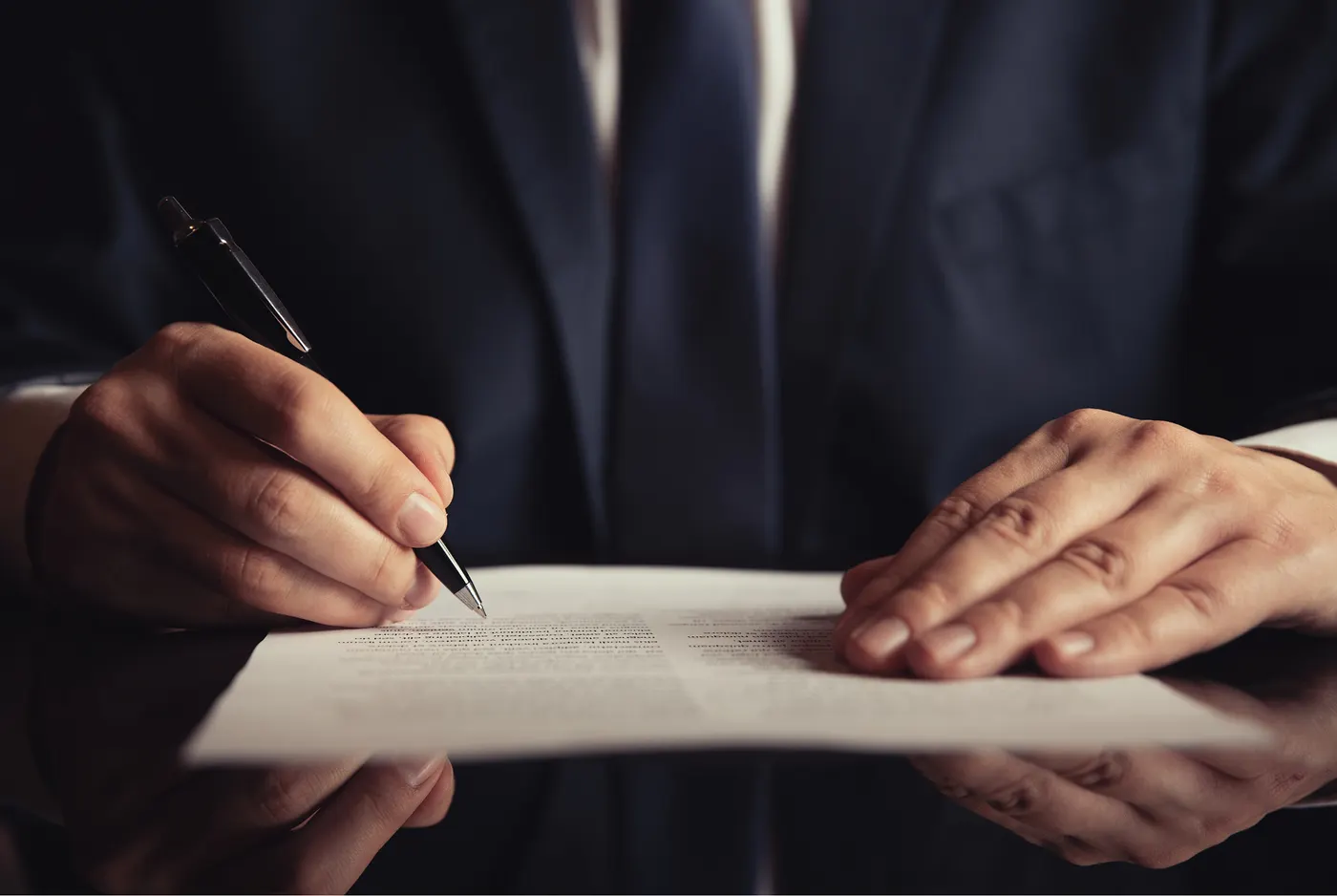 Mano firmando un documento con una pluma