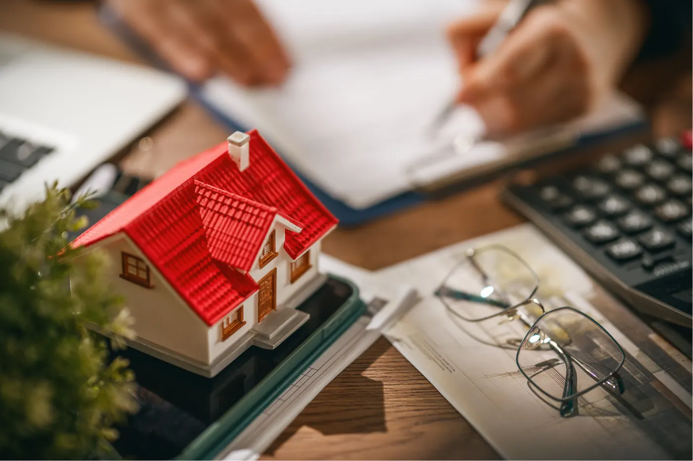 Casa en miniatura junto a una calculadora y documentos